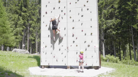 mom and daughter climb a training wall, slow motion