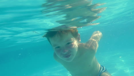 boy swimming underwater in swimming pool