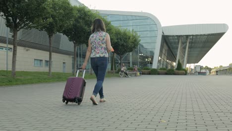 mujer de negocios viajera caminando con equipaje al aeropuerto. niña camina y enrolla la bolsa de la maleta. turismo