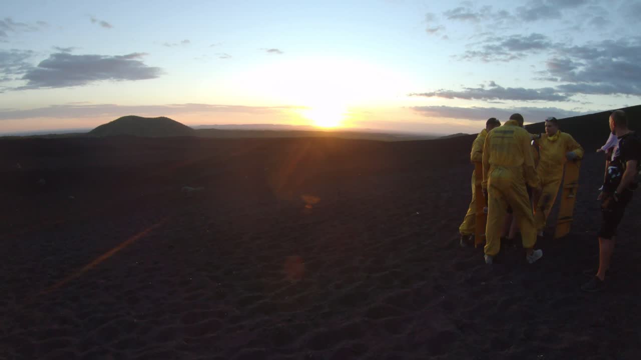 Sunset view from Cerro Negro volcano in Nicaragua, people in protection suit