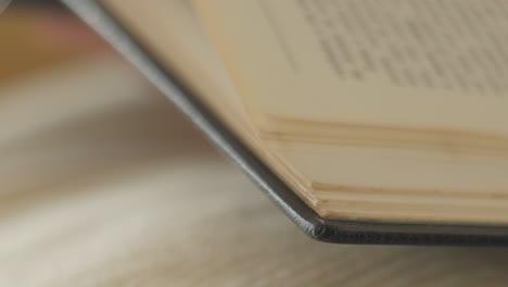 Extreme-close-up-shot-of-human-flipping-pages-of-old-retro-book-on-table