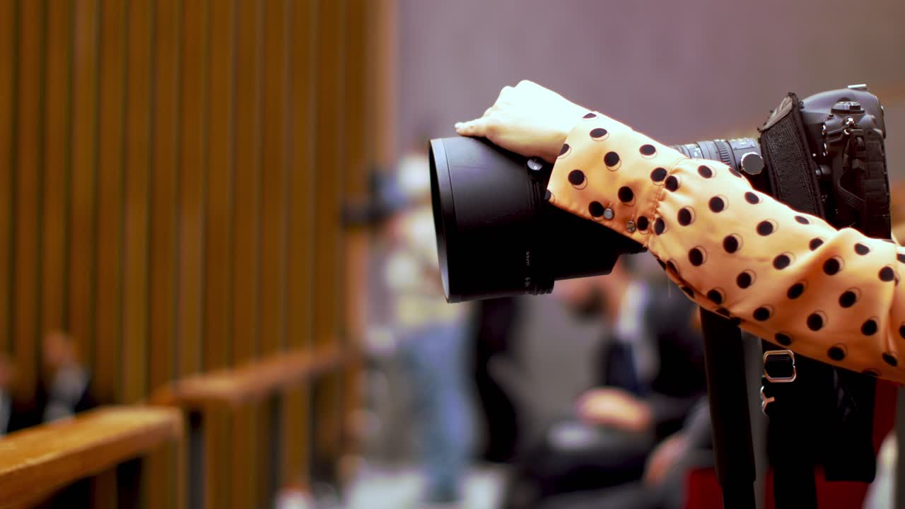 sector mediático de una audiencia judicial, periodista tomando fotos con una cámara