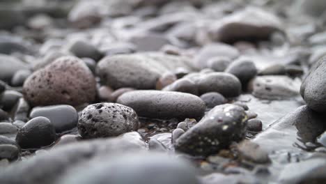 small sea waves passing over round rocks in beach in slow motion