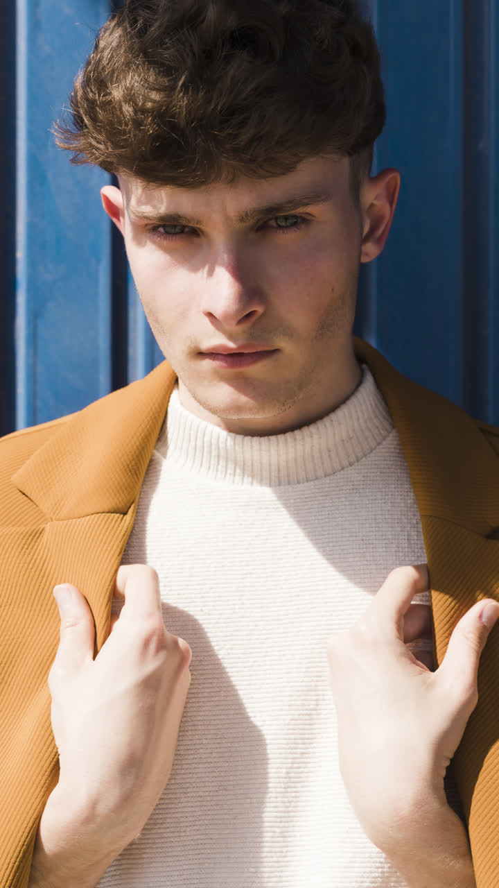 Fashion portrait of a young man in a brown jacket and white turtleneck
