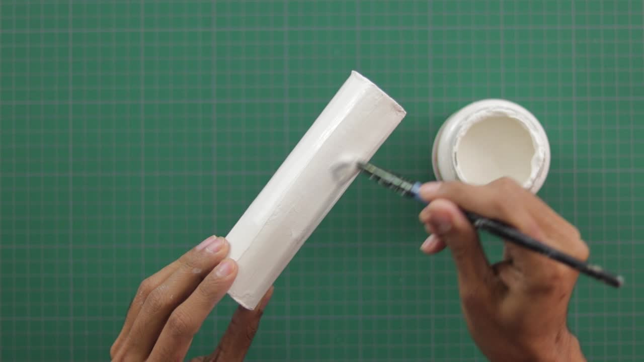 pintura de cilindro de yeso blanco con pincel por encima de la alfombra de trabajo verde