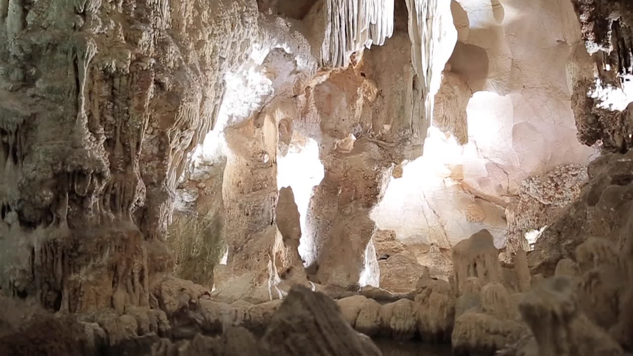 cueva de piedra caliza gigante bajo tierra con estalactitas y estalagmitas blancas que recorren un túnel iluminado