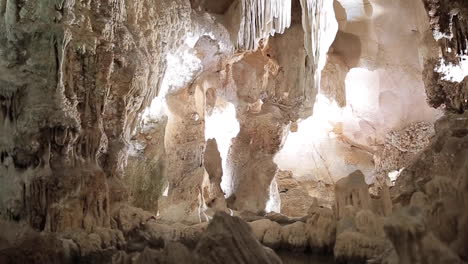 giant limestone cave underground with white stalactites and stalagmites riding through an illuminated tunnel