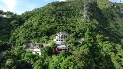 templo clásico en hong kong, rodeado de un exuberante terreno montañoso verde, vista aérea