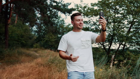 smiling caucasian male speaking via video chat on his smartphone. man spending time in the nature dealing with business issues.