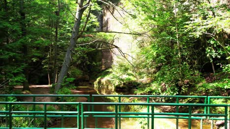 Drone-shot-over-a-small-creek-and-revealing-a-small-walking-bridge-at-Hocking-Hills-State-Park-OH