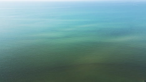 El-Dron-Se-Inclina-Hacia-Abajo-A-Través-De-Las-Aguas-Verdes-Y-Tranquilas-Del-Océano-Atlántico-Y-Se-Ondula-A-Través-De-La-Superficie-Hasta-Los-Malecones-Y-Las-Playas-Costeras.