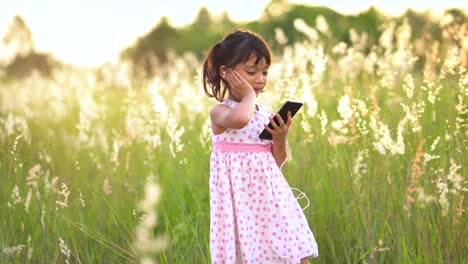 asian girl listen to music and sing happily at the grass fields.
