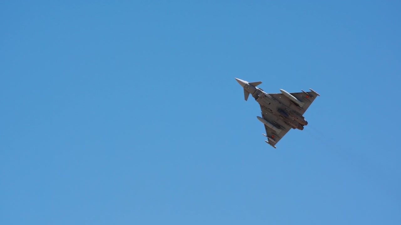 Combat jet climbing away high in blue sky