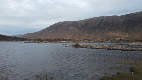 aerial view of caucasian man camping near a lake embraced by mountains in the scottish highlands