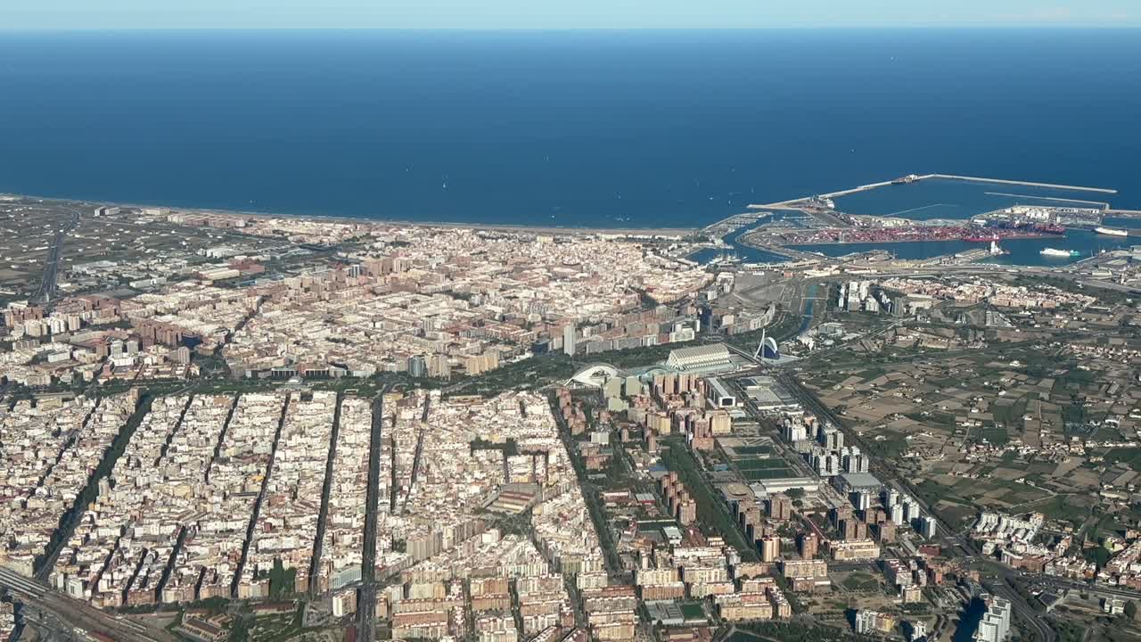Aerial left side view of Valencia city center, harbor and north coast recorded from an airplane cabin departing from the airport in a splendid summer morning with the early light. 4K