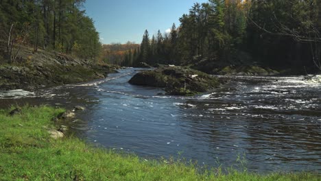 ein fluss, der an einem schönen tag um eine felseninsel fließt, mit herbstfarben im hintergrund