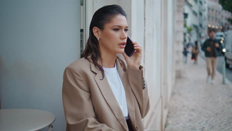 girl freelancer talking cellphone in cafeteria open air close up. serious lady