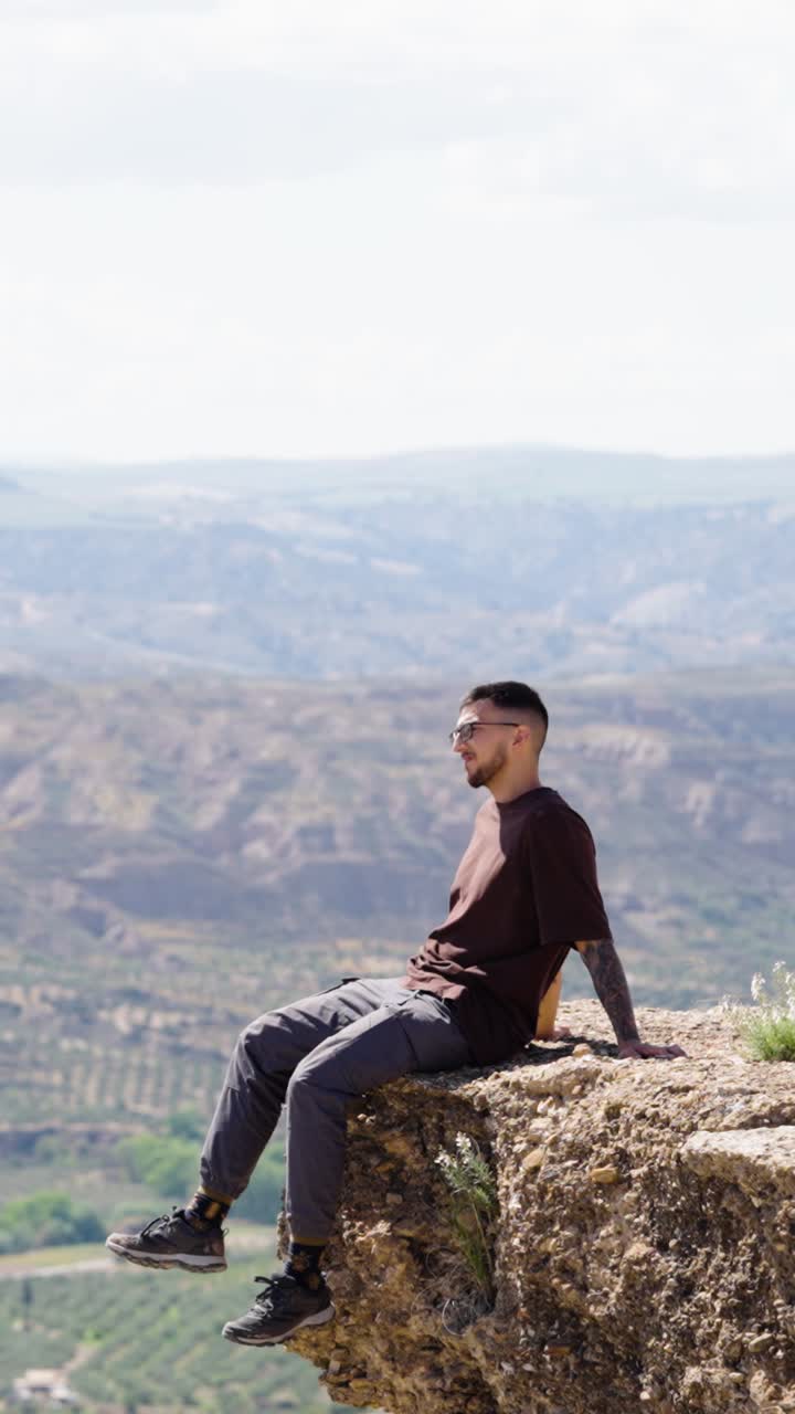 Happy man raising arms on cliff in gorafe, spain. Vertical