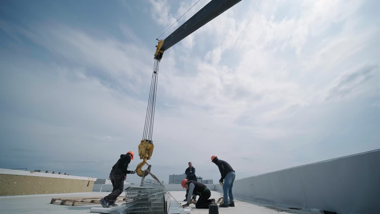 건설 타워 크레인은 지붕에 짐을 들어 올리고 있습니다.