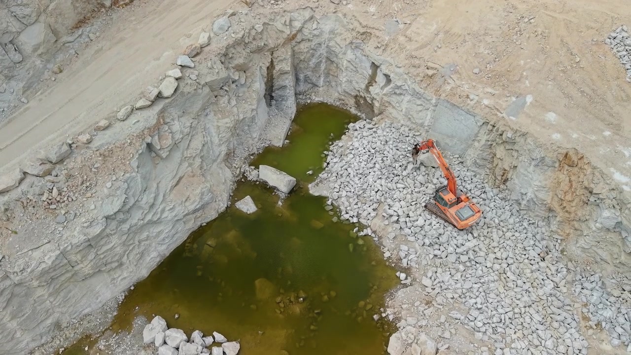 Wide aerial view of excavator in deep stone quarry