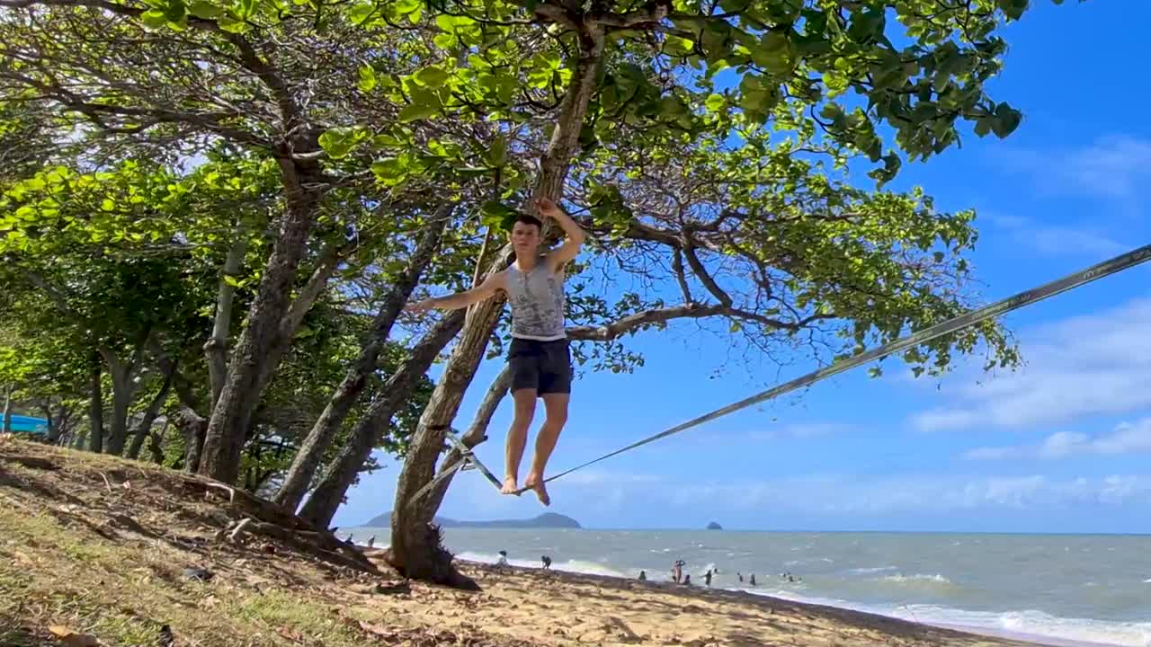 macho adulto joven en slackline en trinity beach en cairns