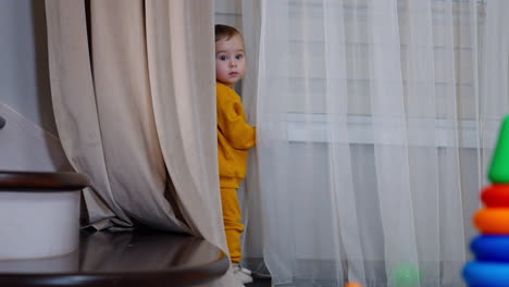 baby hiding behind curtains
