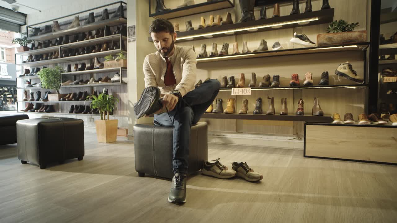 A young, attractive man trying on shoes in a handmade leather shoe store.