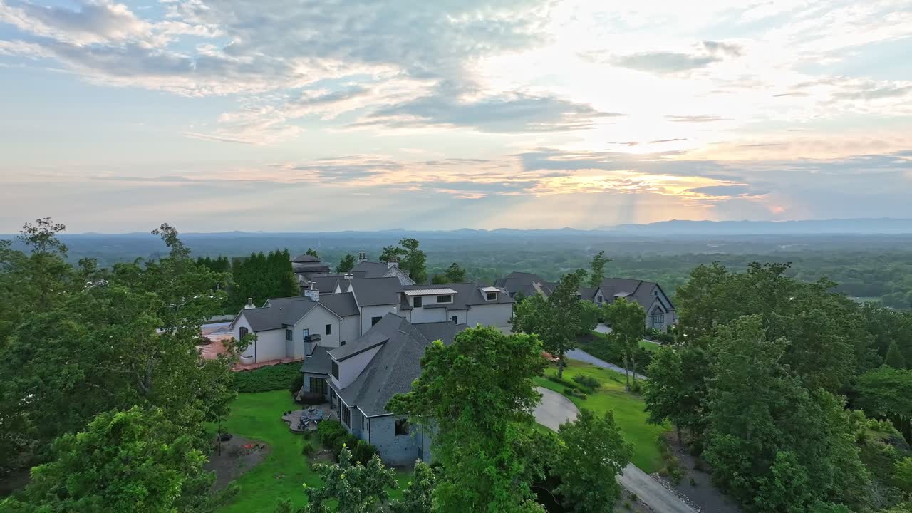 Large houses sit atop a hill in the Montebello Subdivision of Greenville, SC with a mountain range in the background