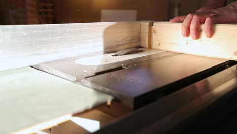 a craftsman rotates and cuts tenons from a piece of wood using a table saw with a dado set in slow motion