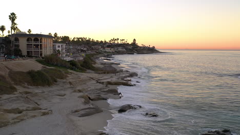 Einsamer-Surfer-Geht-Bei-Sonnenaufgang-Am-Strand-Von-Windansea-Spazieren