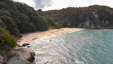 a drone slowly approaching towards a remote beach in new zealand , lonely bay, cooks bay