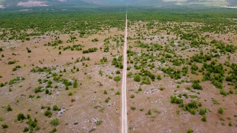 Aerial-Slow-Reveal-Of-A-Straight-Road-Cutting-Through-The-Beautiful-Croatian-Desert-Landscape