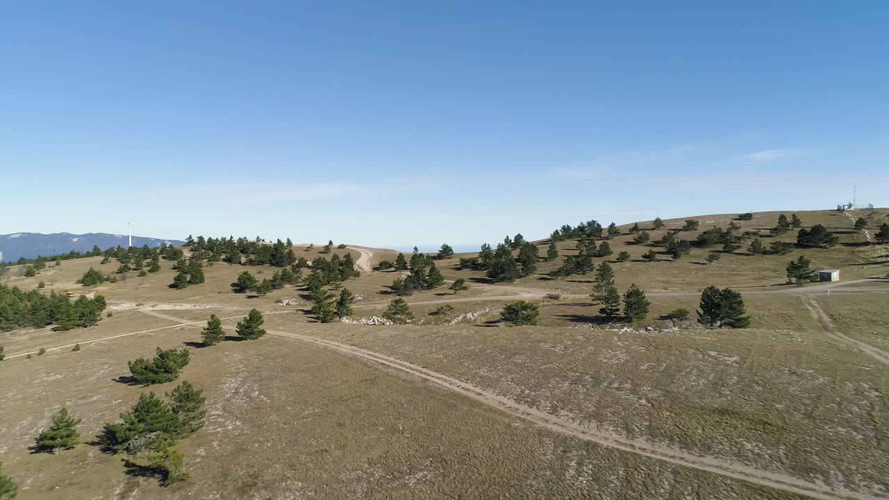Paesaggio montuoso con sentieri e turbina eolica