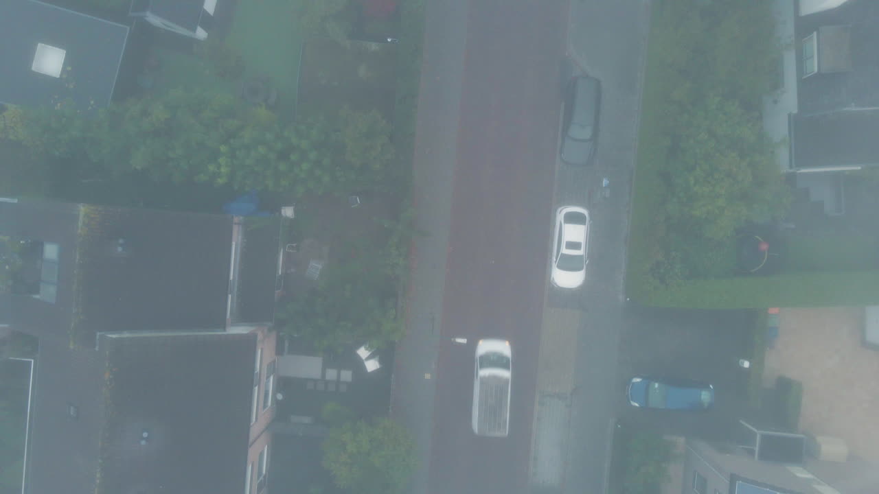 고요한 교외 도로에서 안개를 뚫고 운전하는 자동차의 하향식 공중