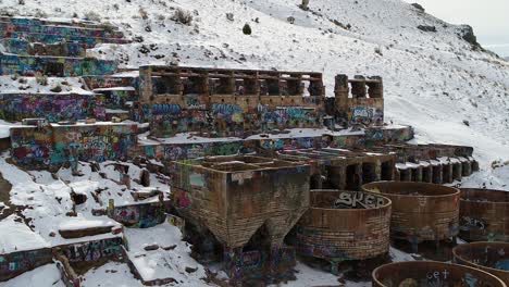 a drone orbits the rusty old tintic mill in geneloa, utah, revealing the decaying water tanks, leaching tanks, roasters and crusher built in 1920