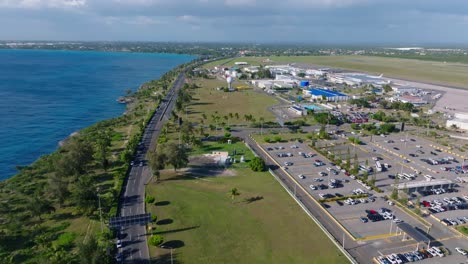 aerial flight over highway with traffic and parking area of las américas international airport during sunny day on dominican republic