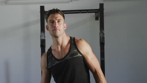 hombre caucásico en forma sonriente dirigiéndose a la cámara dentro del gimnasio