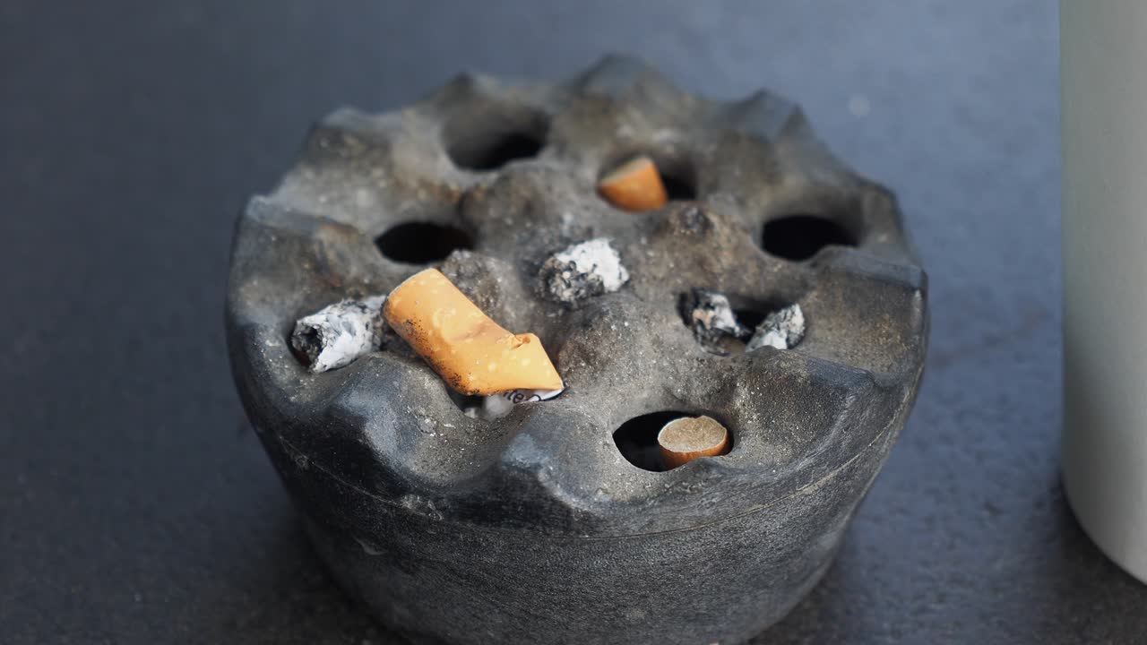 cenicero usado con colillas de cigarrillo