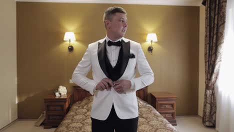 groom getting ready in white tuxedo