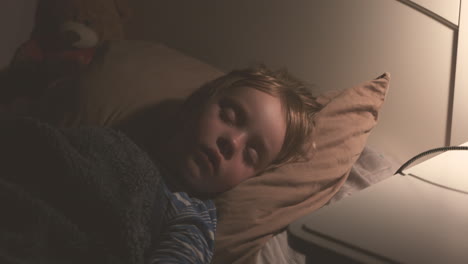 adorable niño dormido en la cama por la noche