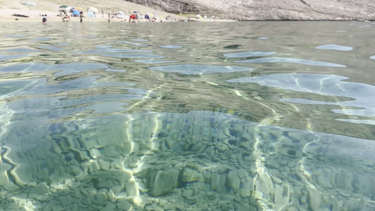 Clear sea water with barren land reflections on island Pag's beach Metajna in Croatia, summer