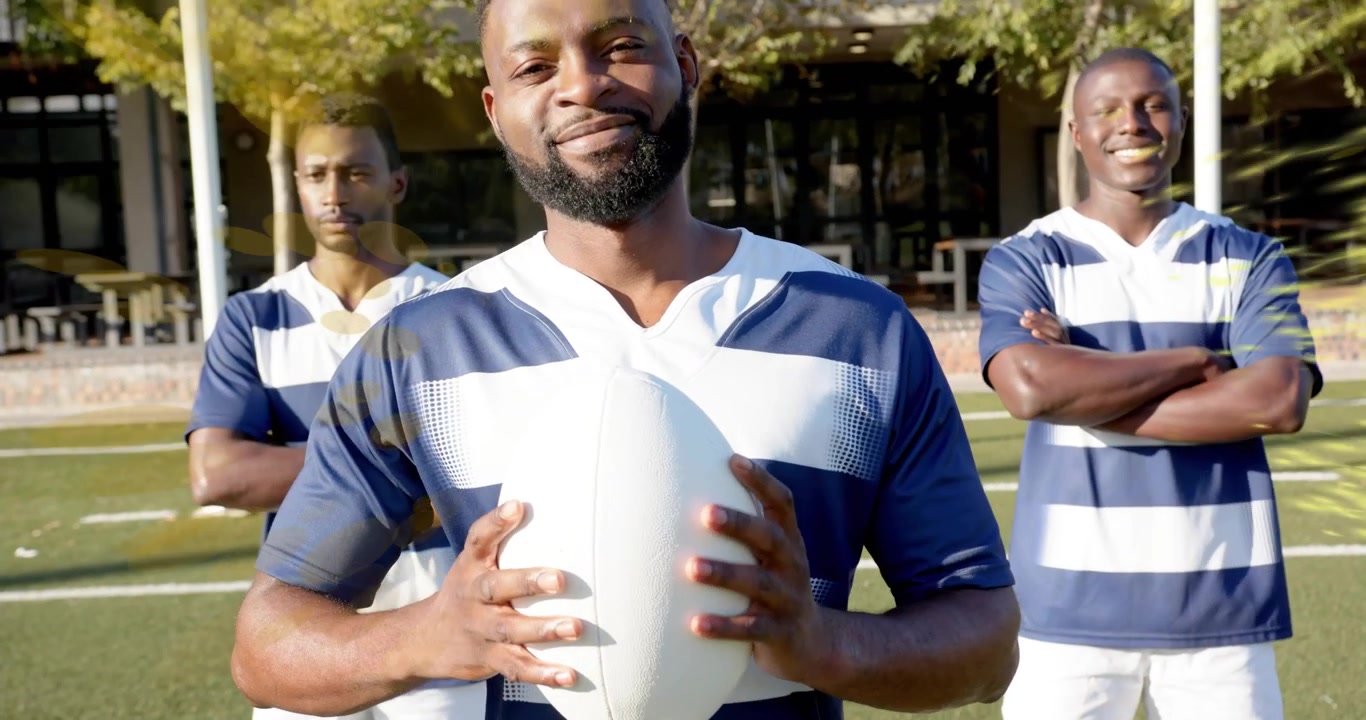 Giocatori di rugby che posano in una pubblicità, ricevendo polvere gialla da un palo della porta che spazza da destra, rivelando l'unità della squadra.