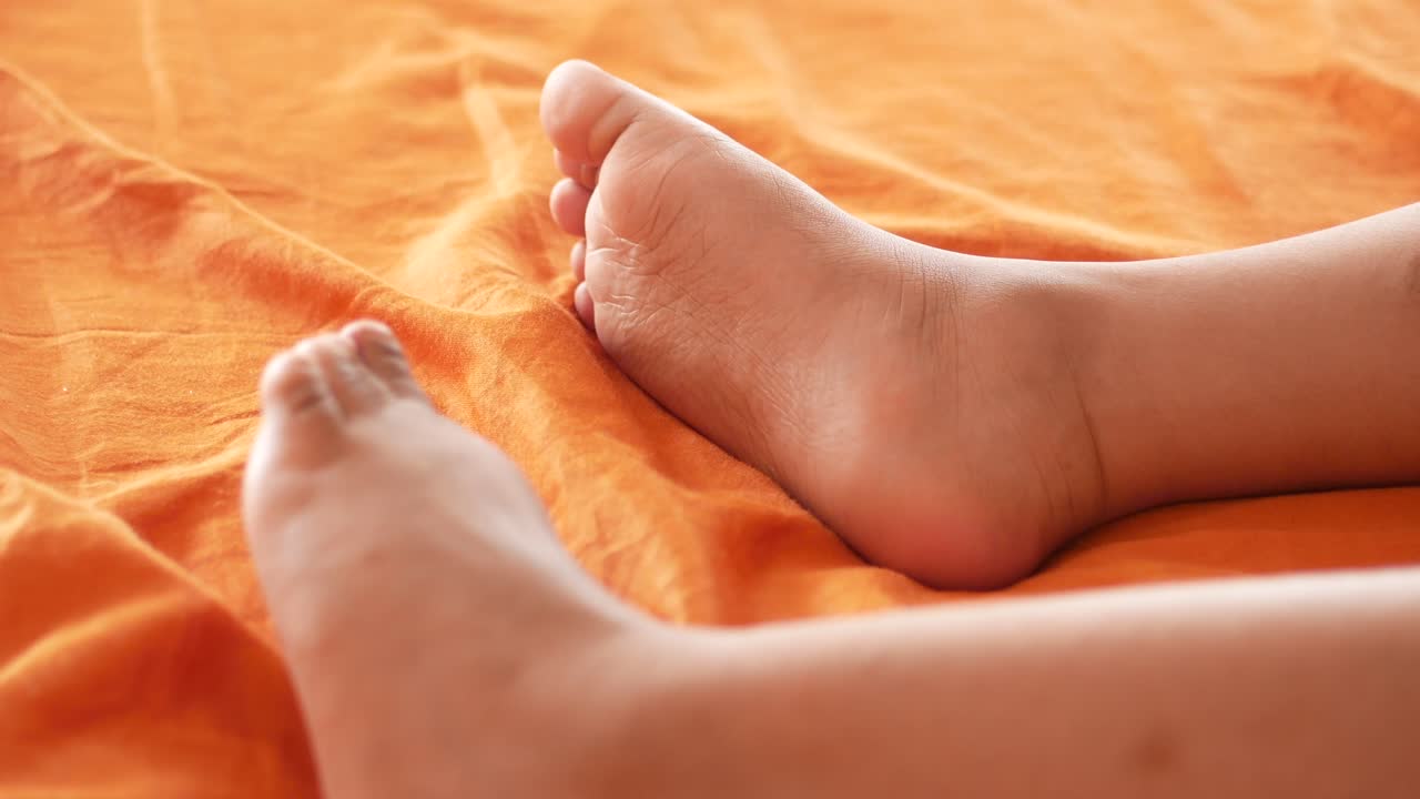 오렌지색 침대 시트 에 있는 아이 의 발