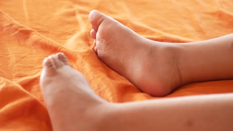 los pies del niño en una sábana de cama naranja