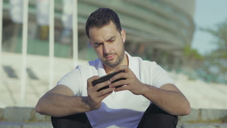 Focused-bearded-man-playing-video-game-on-smartphone.