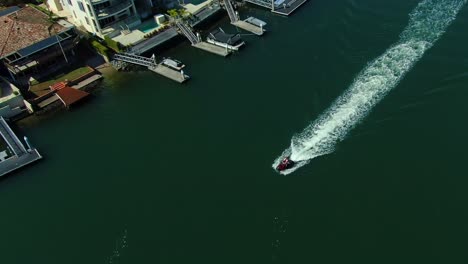 Jet-ski-rider-cruising-past-luxury-homes-in-a-Gold-Coast-canal-at-Beautiful-Surfers-Paradise-Australia