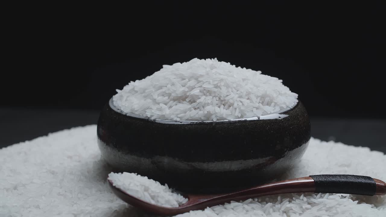 Soft White Rice In The Wooden Bowl And Spoon Rotating In A Slow Motion, Over White Rice Background