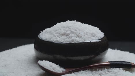 soft white rice in the wooden bowl and spoon rotating in a slow motion, over white rice background