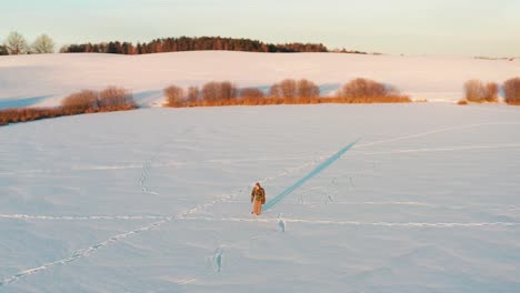 Vista-Aérea-Circular-De-Una-Persona-Patinando-Sobre-Hielo-En-Un-Estanque-Congelado-Durante-La-Hora-Dorada-Del-Invierno