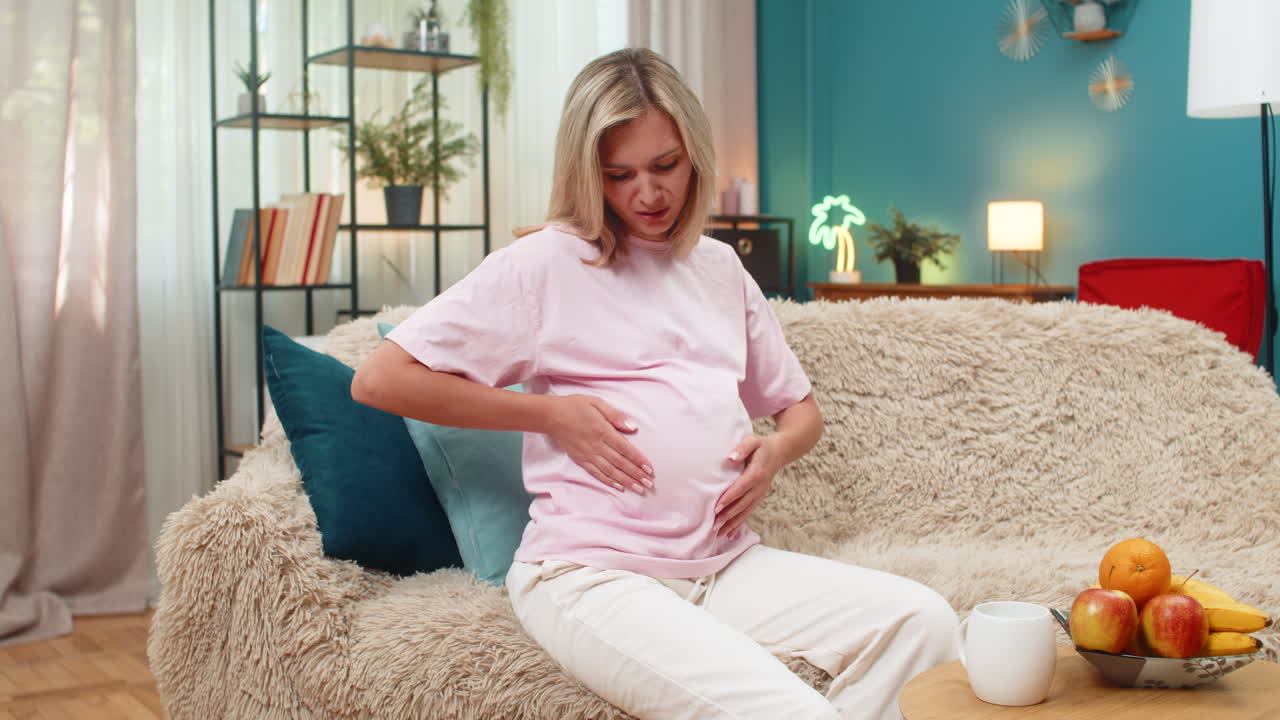 Pregnant woman clutching stomach feeling abdominal pain cramps showing discomfort during pregnancy